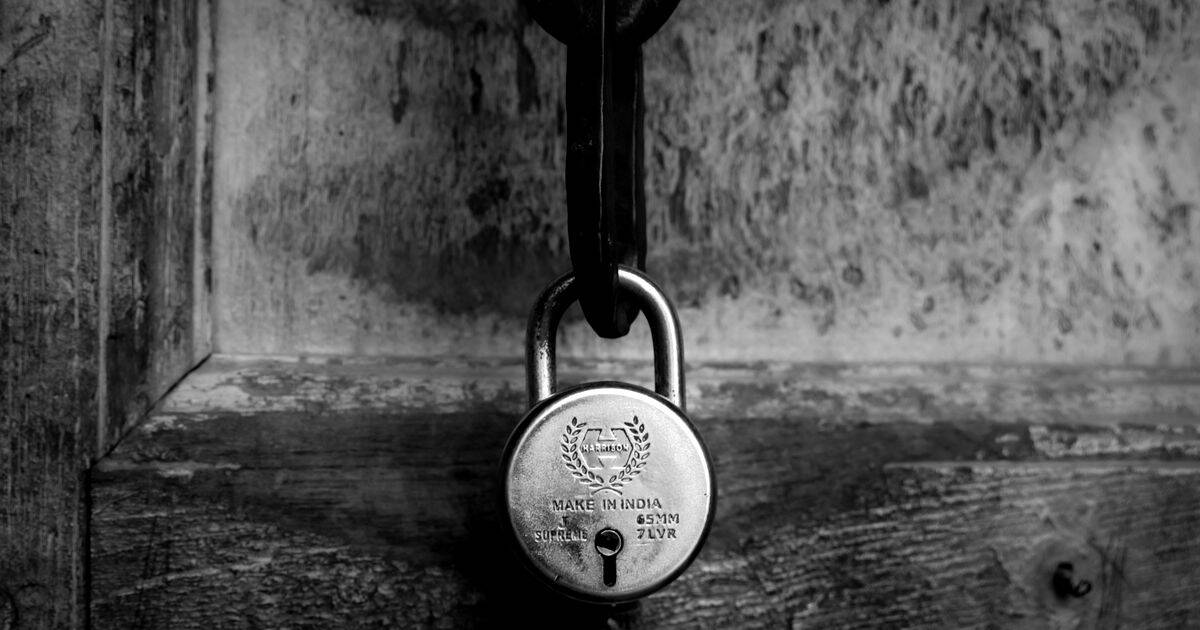 Candado antiguo cerrando una puerta de madera, en blanco y negro