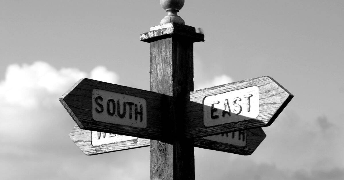 Poste de senales indicando varias direcciones, en blanco y negro