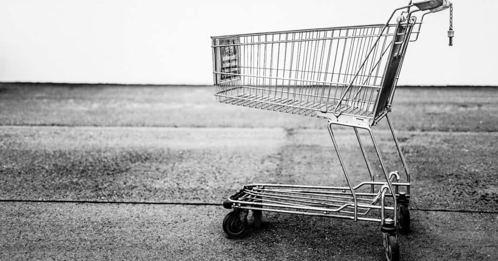 Carrito de la compra vacío sobre el asfalto, en blanco y negro